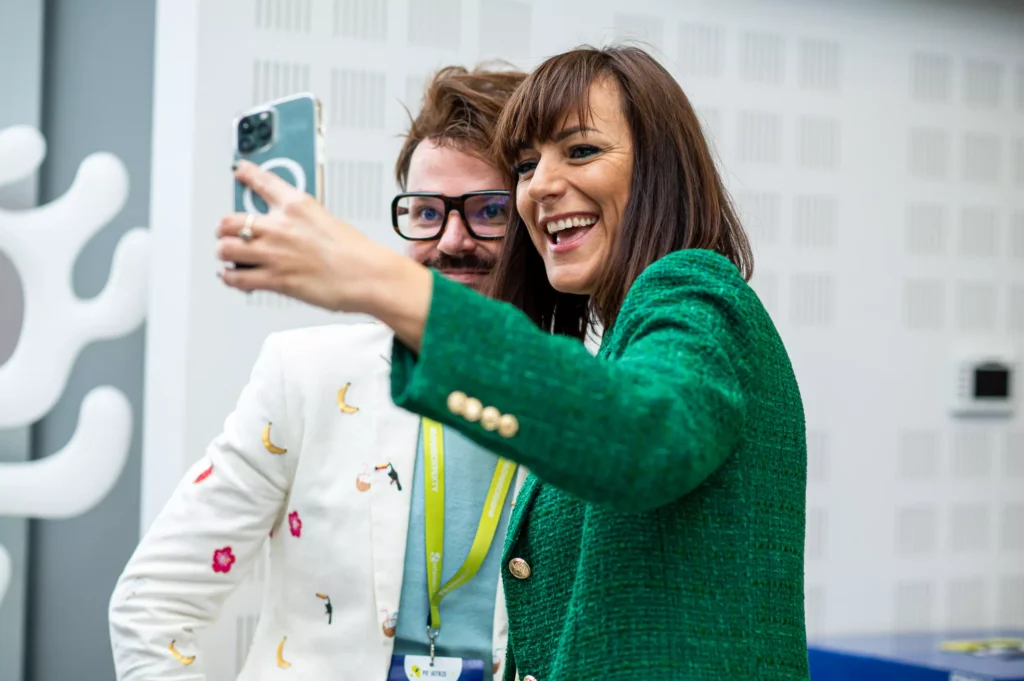 pani w zielonej marynarce robi sobie selfie z panem w okularach podczas konferencji