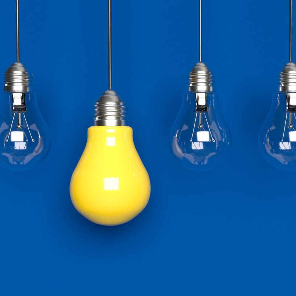 cztery żarówki na niebieskim tle jedna się świeci na żółto
