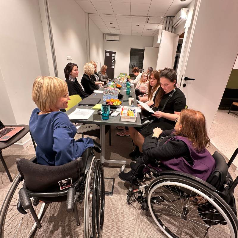 grupa kobiet z niepełnosprawnościami siedząca dookoła stołu