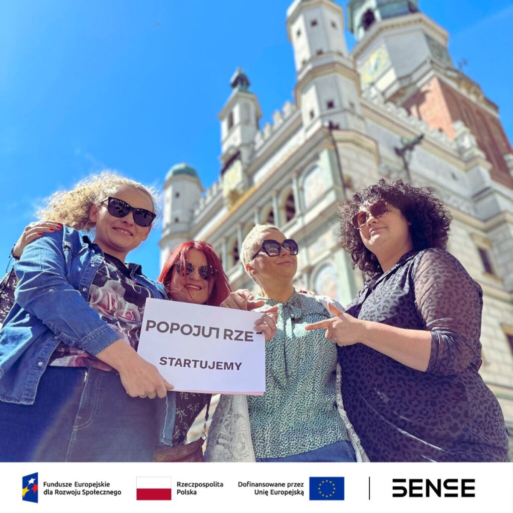 cztery kobiety na tle ratusza poznańskiego z kartką "popojutrze start"