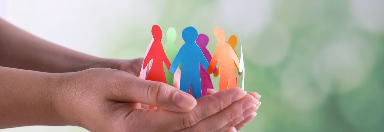 wycięte z papieru postacie symbolizujące osoby o szczególnych potrzebach na tle ludzkich dłoni