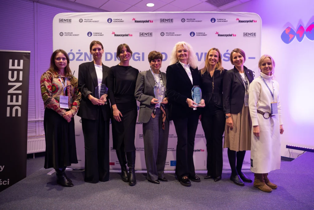 grupa ludzi na scenie pozujących do zdjęcia mają w rękach statuetki