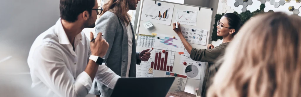 grupa ludzi przy tablicy z wykresami