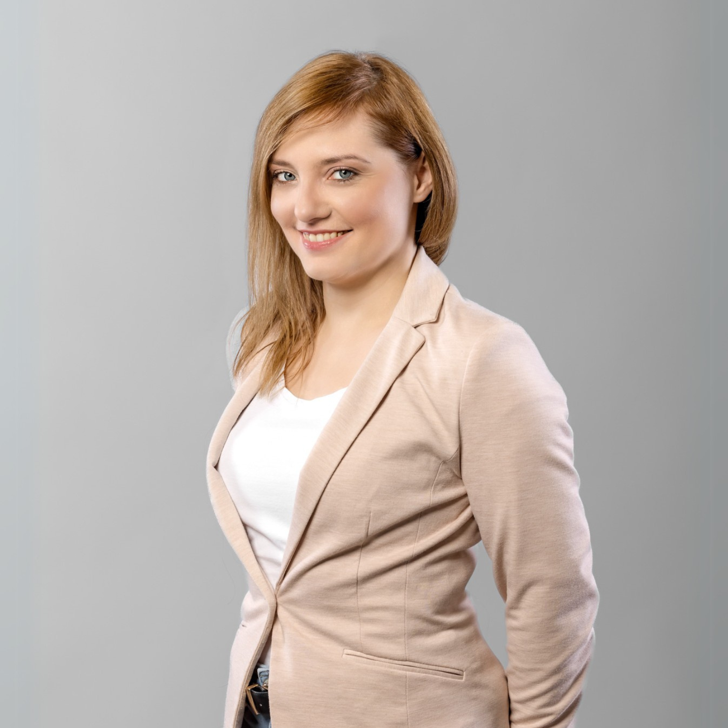 Portret uśmiechającej się kobiety w biznesowym stroju, w nowoczesnym biurze z jasnym oświetleniem.