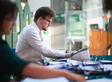 mężczyzna w białej koszuli przy stoliku robi coś na komputerze