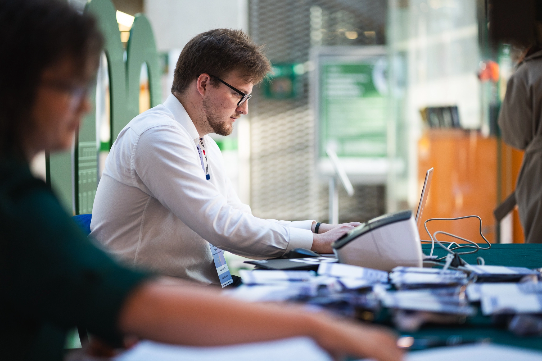 mężczyzna w białej koszuli przy stoliku robi coś na komputerze