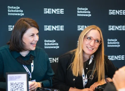 Dwie kobiety uśmiechające się na czarnej ściance SENSE