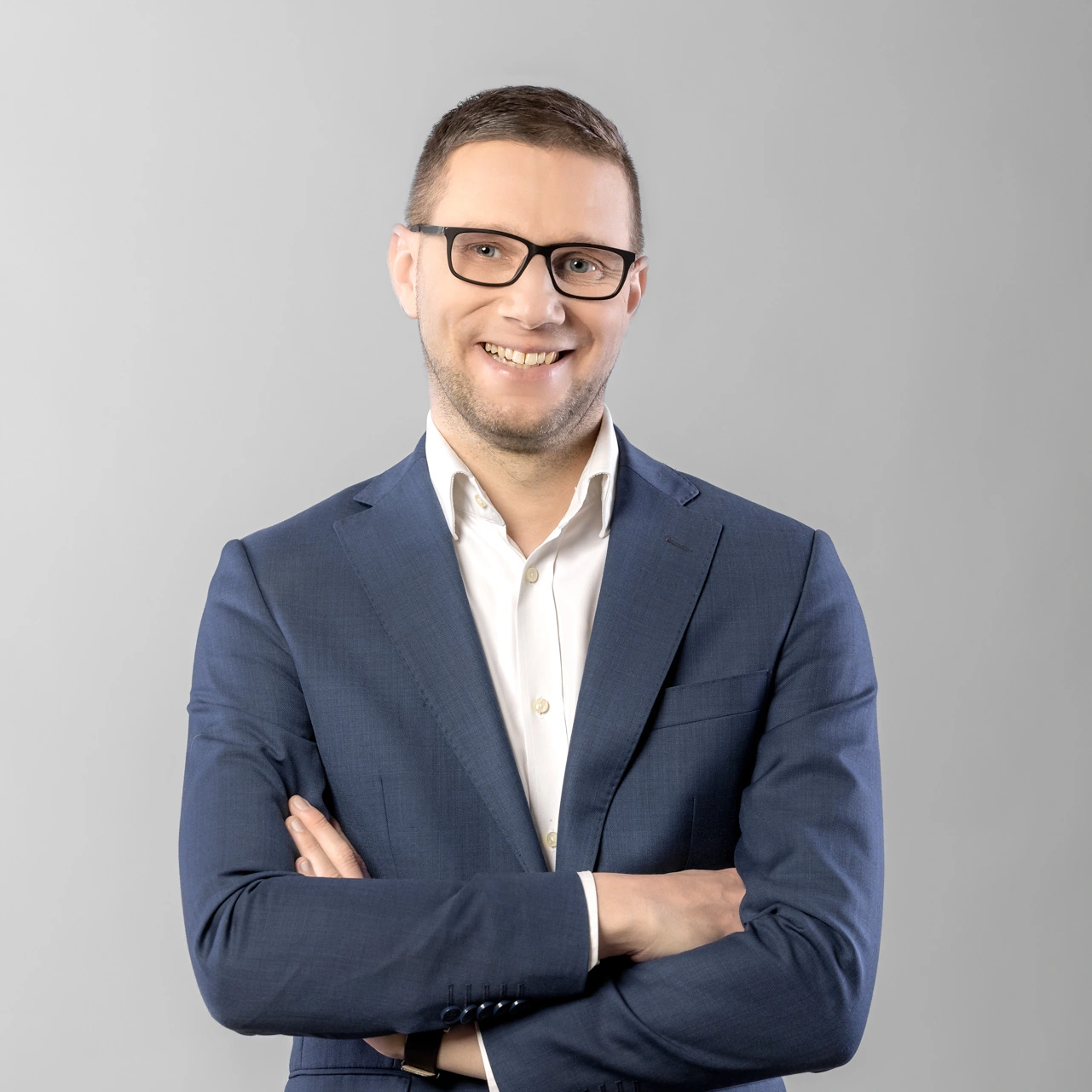 Uśmiechnięty mężczyzna w okularach białej koszuli i granatowym garniturze