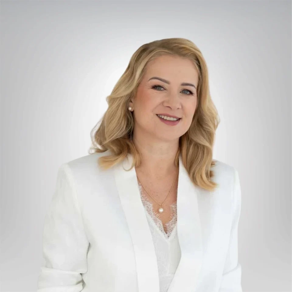 Uśmiechnięta kobieta w blond włosach i białej marynarce
