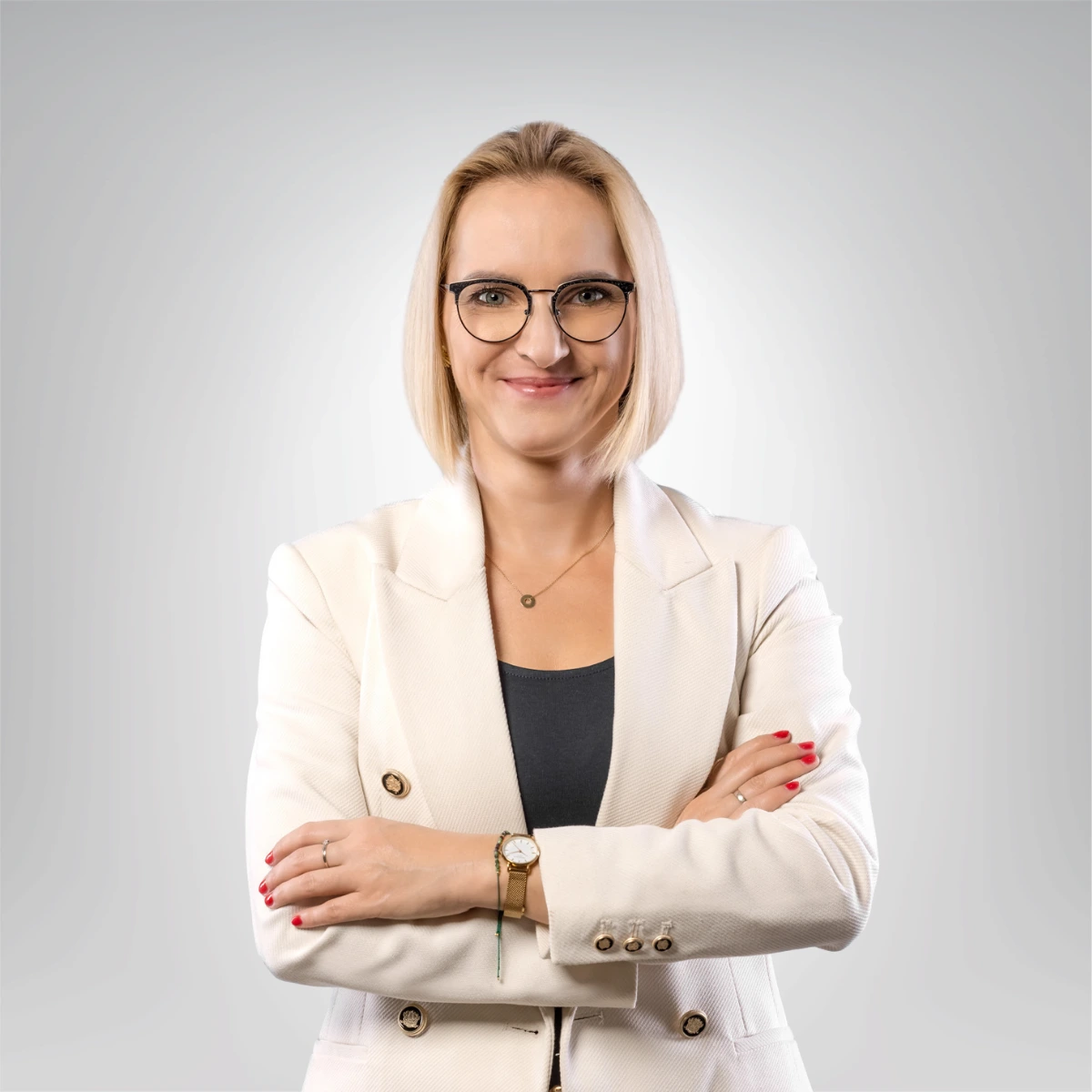 Portret kobiety w beżowej marynarce z krótkimi blond włosami i uśmiechem na twarzy