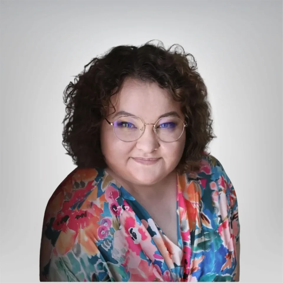 uśmiechnieta kobieta w okularach i kręconych włosach w kolorowej bluzce