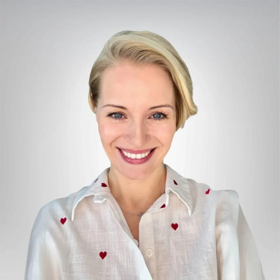 uśmiechnięta kobieta w krótkich blond włosach ma na sobie białą koszulę