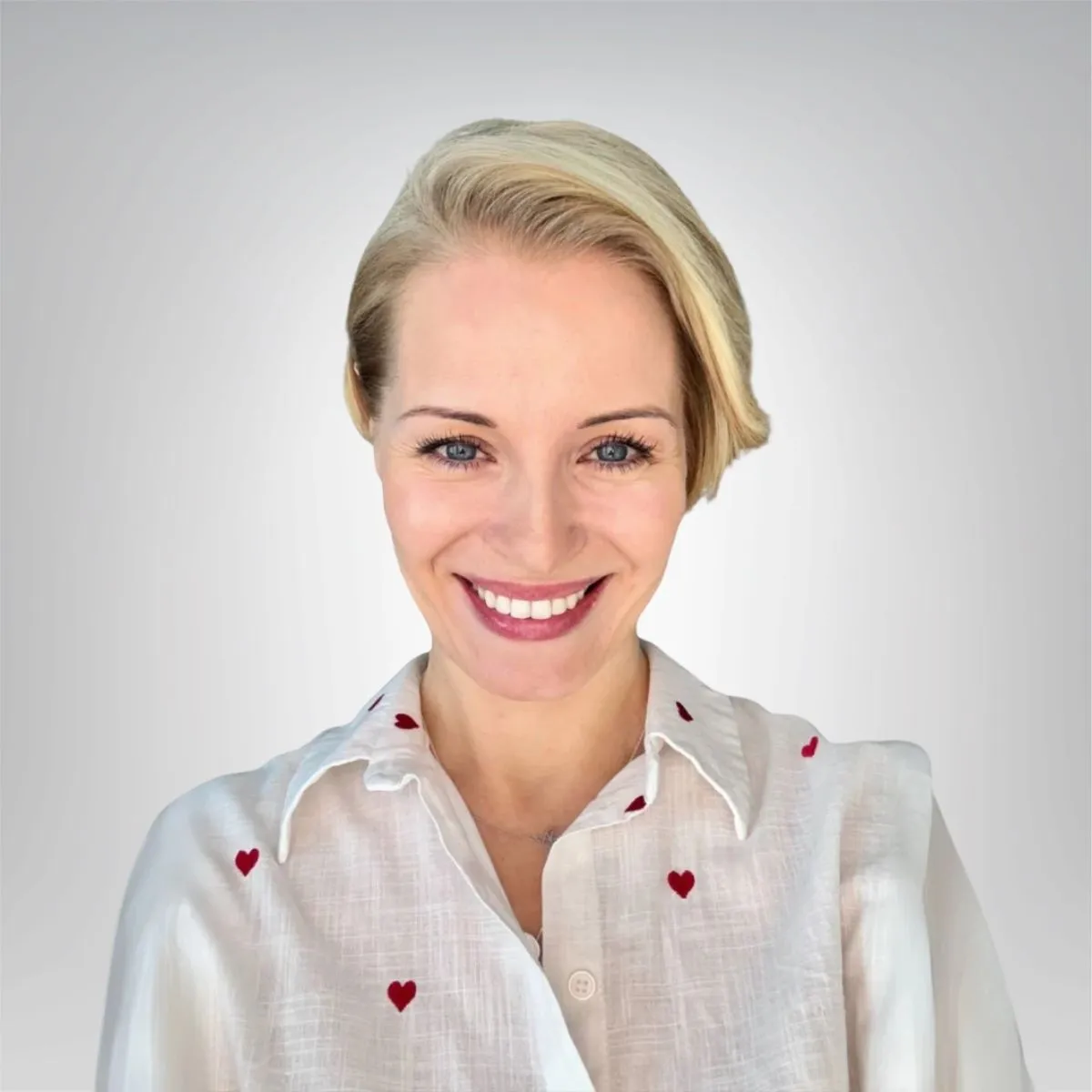 uśmiechnięta kobieta w krótkich blond włosach ma na sobie białą koszulę